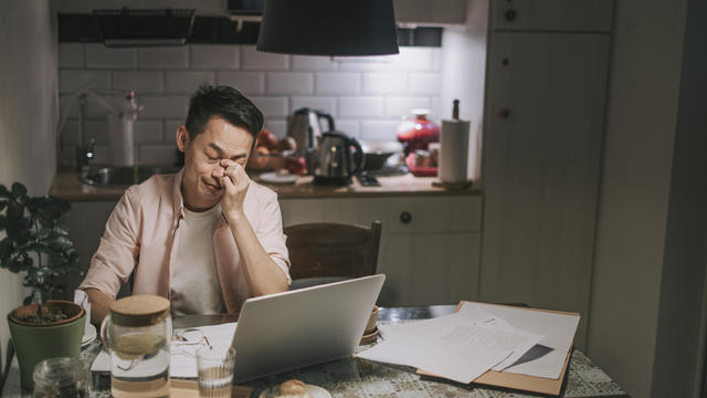 night overwork Asian chinese male working late at home dining room emotional stress with his financial bill alone at night 