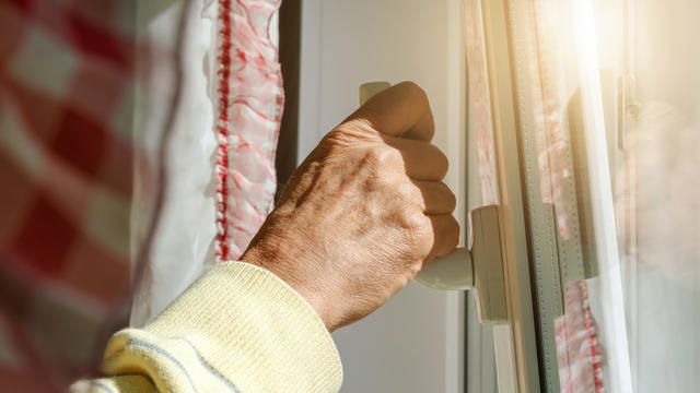old person hand holds plastic window handle under sunlight 