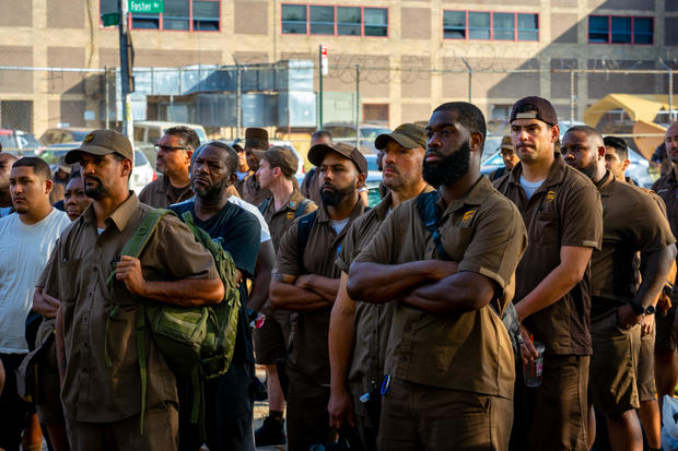 Crowd of UPS workers in uniform standing with arms crossed 