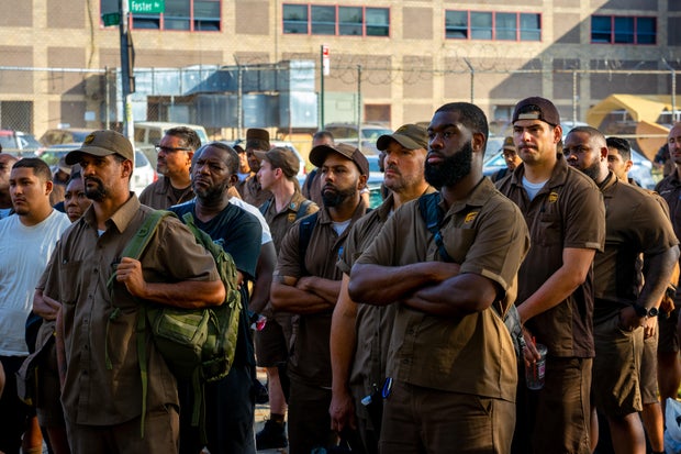 Crowd of UPS workers in uniform standing with arms crossed