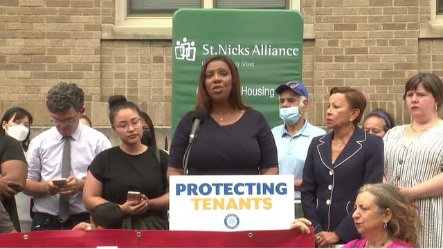 Attorney General Letitia James stands at a podium alongside several other individuals. 
