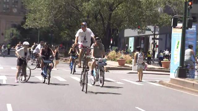 Several people on bicycles ride down the street. 