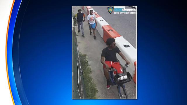 A surveillance photo shows a teenager on a bicycle while two other teens walk behind him. 