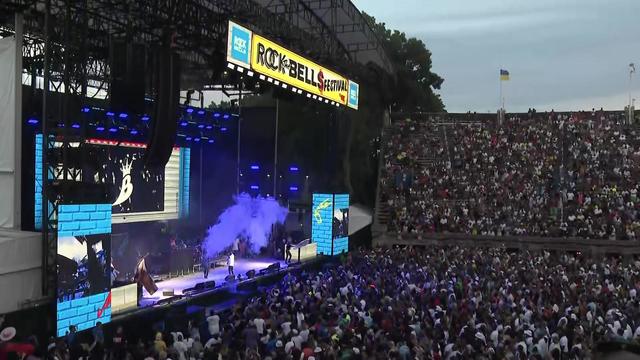 Artists perform on stage at Forest Hills Stadium as hundreds of concert-goers watch. 