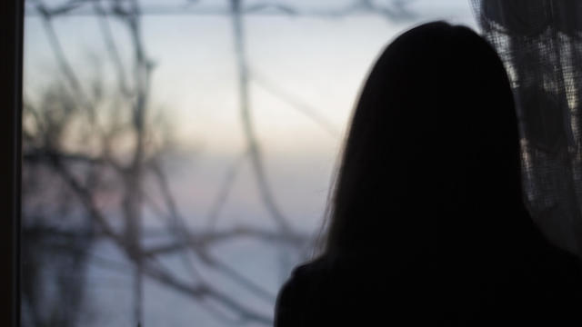 Silhouette girl on dark window in house - depression, danger, blur 