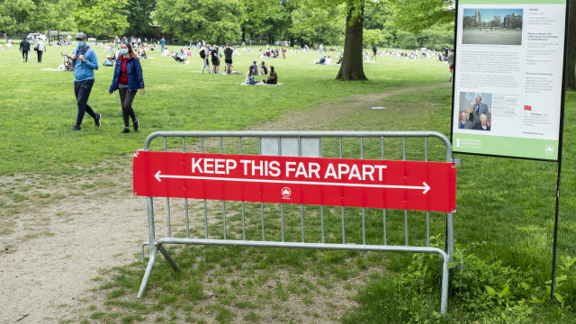 On Memorial Day weekend, a sign at the entrance of Sheep Meadow in Central Park says "Keep this Far Apart" physically showing how far 6 feet is with crowds of people in side the park. 