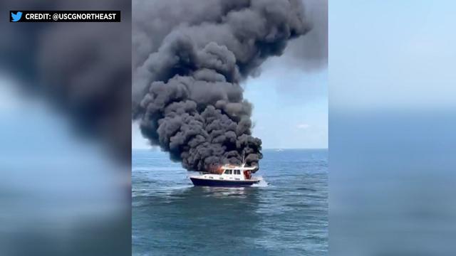 Black smoke billows from a 38-foot vessel on the water. Flames can be seen. 