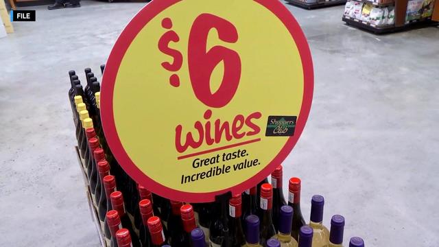 A sign on a display of wine bottles inside a store reads, "$6 wines. Great taste. Incredible value." 