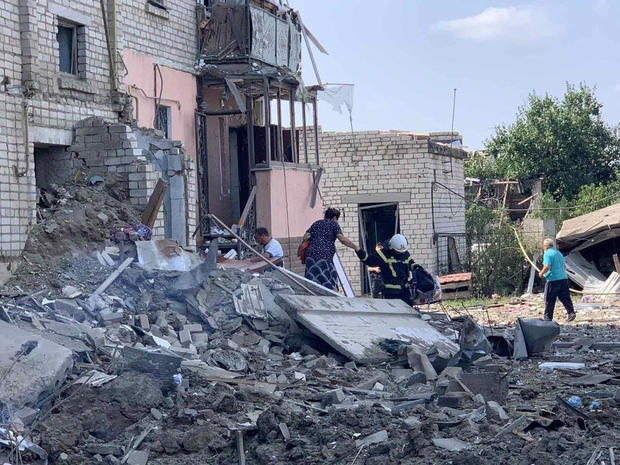 A rescuer helps a woman to be evacuated from a residential building damaged by a missile strike amid Russia's attack on Ukraine, in Voznesensk, Ukraine, August 20, 2022. 