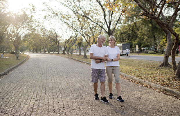 Senior citizen couple walking in a park on a summer morning.  Senior couple spend time together in public park 
