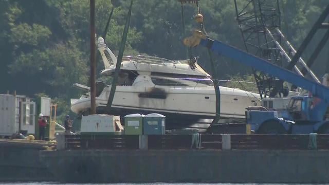 A crane is used to lift a yacht out of the Hudson River. 