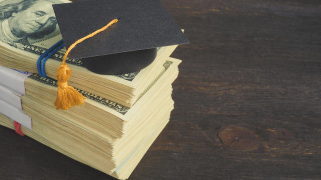 Savings for education and university concept. Stack of cash and graduation cap. 