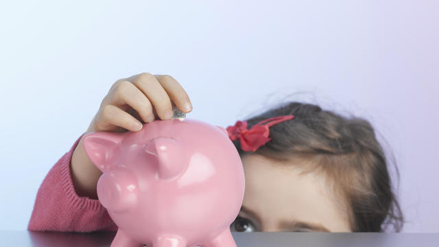 Girl putting coin in piggy bank 