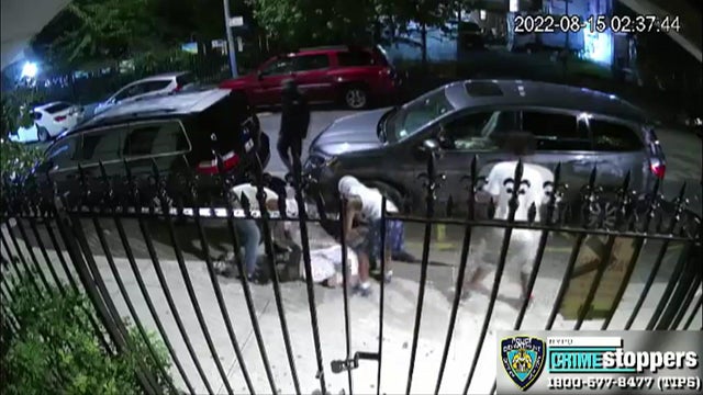 Surveillance video shows several suspects allegedly robbing a man laying on a sidewalk. 