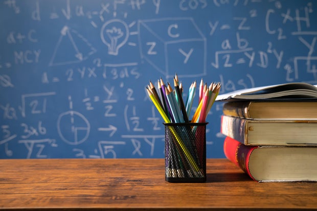 Back to school supplies. Books and blackboard on wooden background