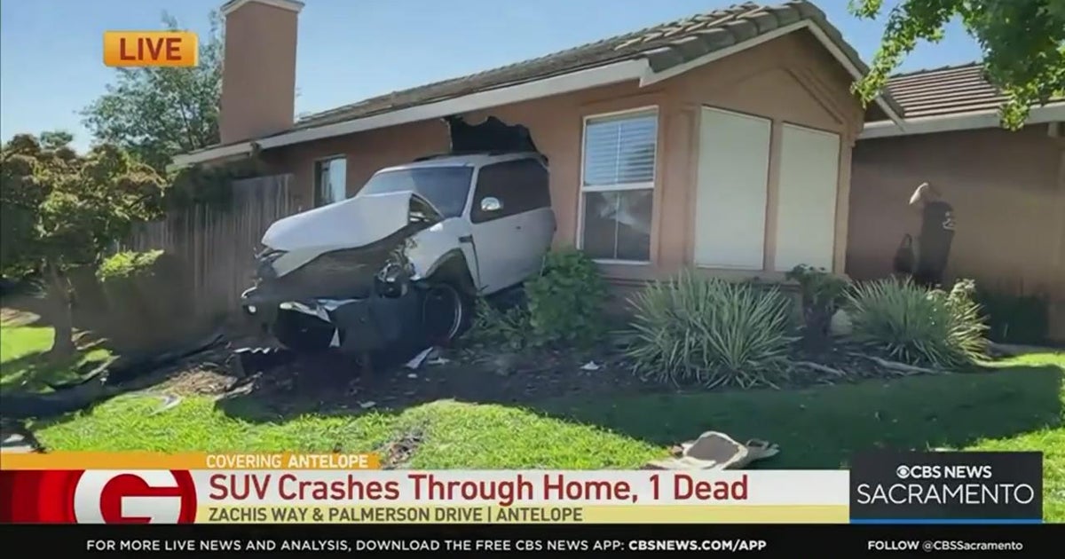 Vehicle crashes through home, 1 dead