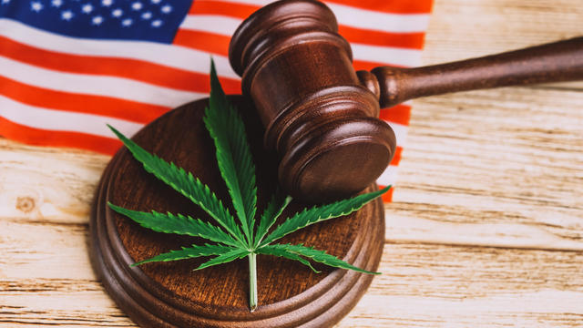 Cannabis leaf on sound block under gavel over US flag. 