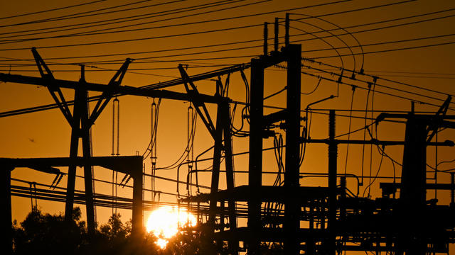 Sun sets behind power lines, backed by orange sky 