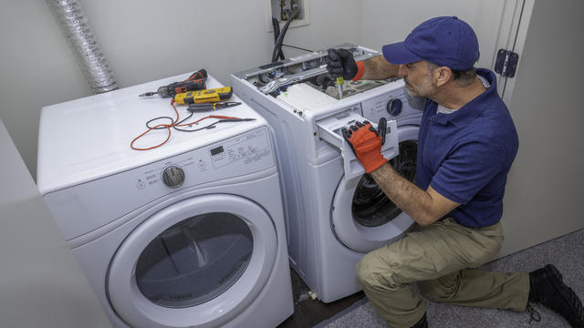 Appliance technician working on a front load washing machine in a laundry room 