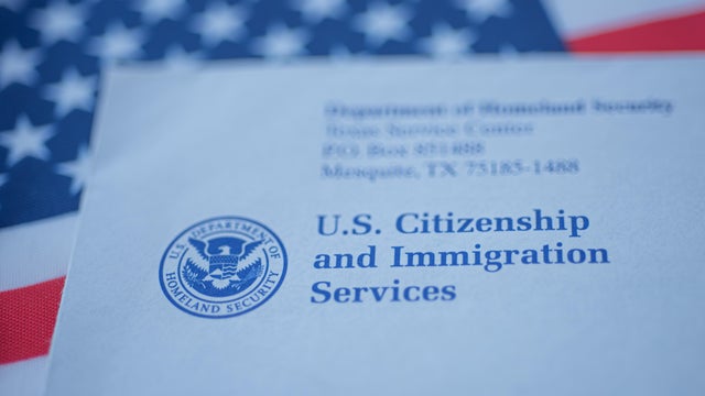 Hand touching Letter (Envelope) from USCIS on  flag of USA background. 
