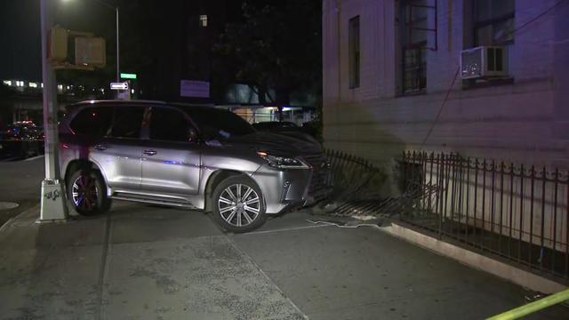 An SUV sits on a sidewalk where it has partially knocked down a piece of fencing. 