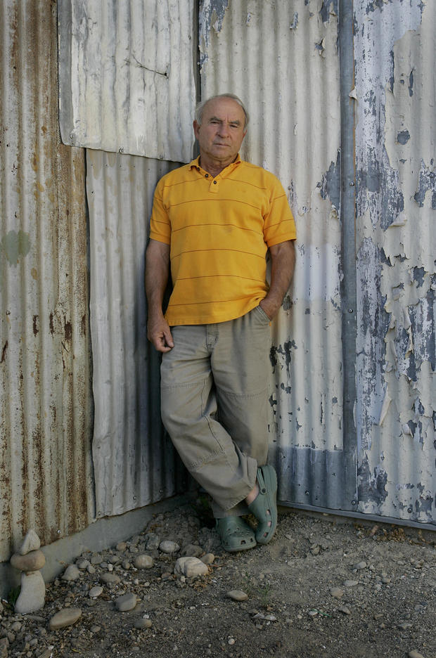 Man in yellow polo in front of tin shed 