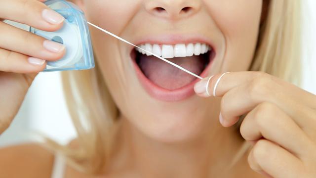 Woman using dental floss, cropped 