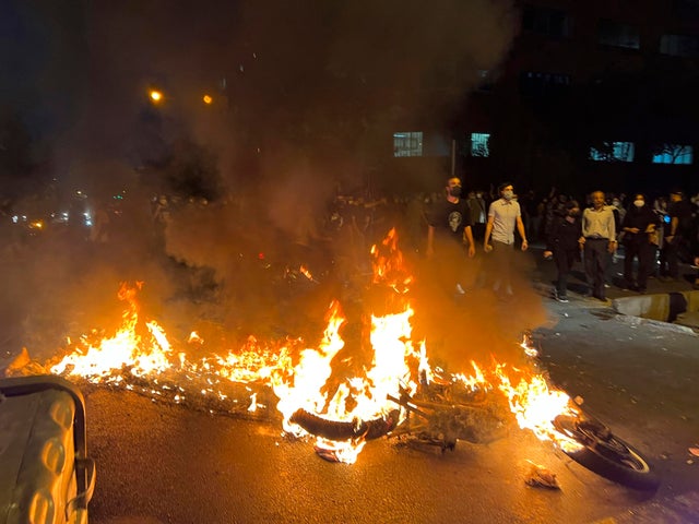 A photo taken by an individual not employed by the Associated Press and obtained by the AP outside Iran shows a police motorcycle burning during a protest over the death of a young woman who had been detained for violating the country's conservative dress code, in downtown Tehran, Iran, Sept. 19, 2022.