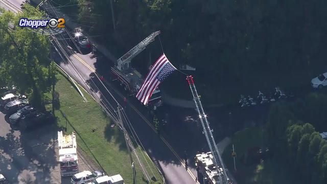 A large American flag flies from tower ladders over a street in Shrub Oak. 