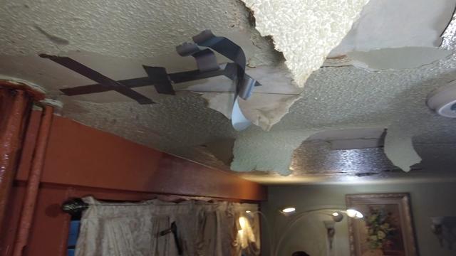 A shot of the ceiling of a NYCHA apartment. Pieces of the ceiling are peeling off and cracks have been covered with duct tape. 
