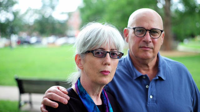 White-haired woman and bald man standing in a park 