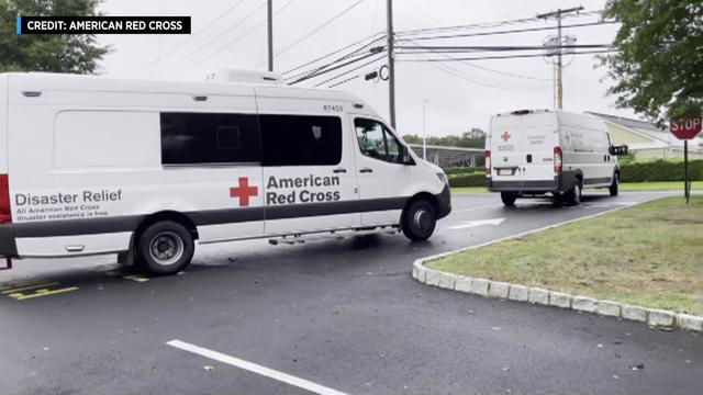Two American Red Cross disaster relief vehicles leave a parking lot in New Jersey. 