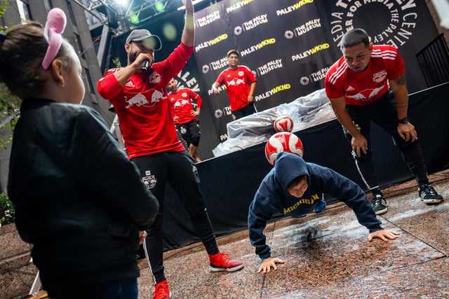 Red Bull's Freestyle Crew does soccer tricks with a volunteer from the public at PaleyWKND outside the Paley Museum on October 01, 2022 in New York City. 