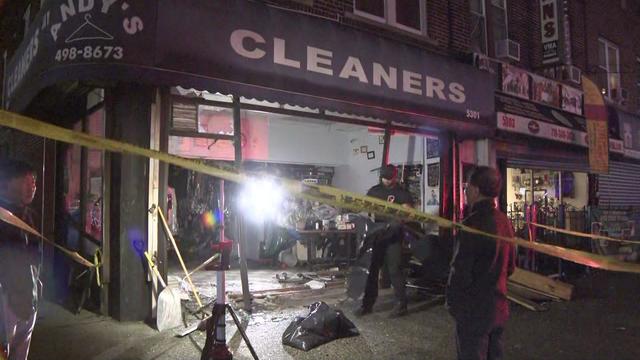 Crime scene tape blocks off a dry cleaners. The front of the store has been completely destroyed, leaving a large hole where the front window and door were. 