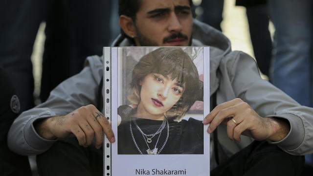 A man with a photograph of Iranian woman Nika Shakarami, 