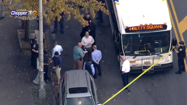 An aerial shot of people standing next to a bus blocked off by crime scene tape. 