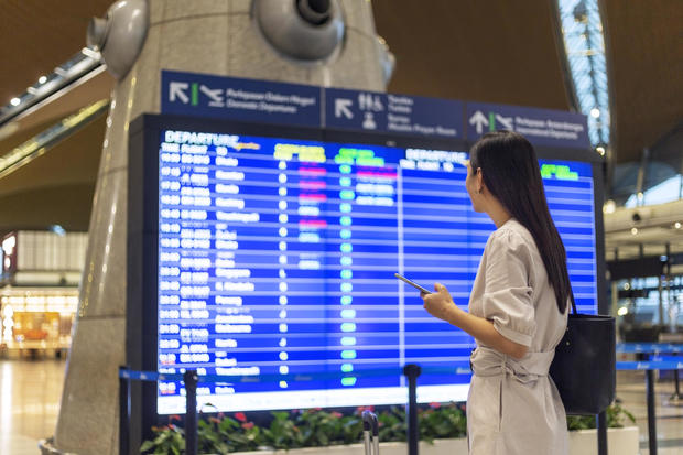 Let the journey begin, woman looking flight timetable board. 
