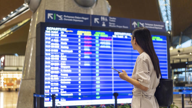 Let the journey begin, woman looking flight timetable board. 