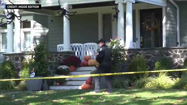 A police officer walks in front of a home surrounding by crime scene tape. 