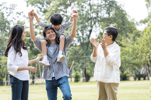 Multi Asian family spending time on weekend vacation.  Young father carrying piggyback together happily in public park. 