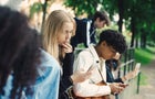 Male and female friends using smart phones in park 