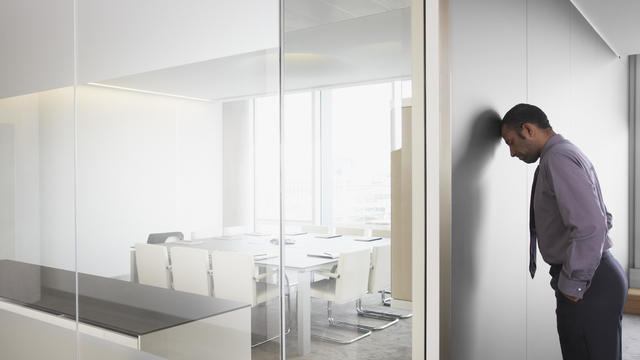 Businessman leaning on corridor wall 