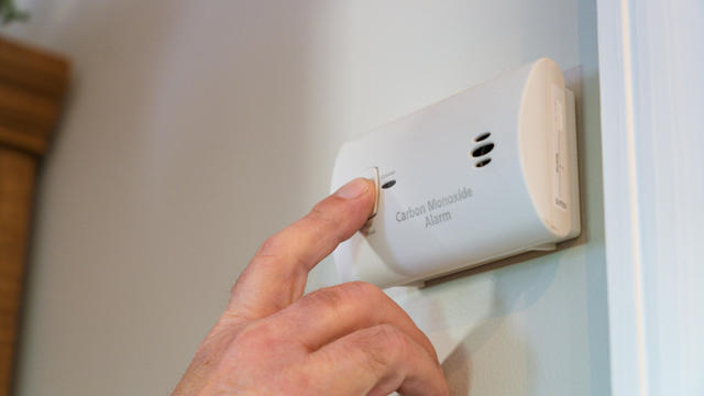 Man's Hand Testing Electrical Carbon Monoxide Alarm 