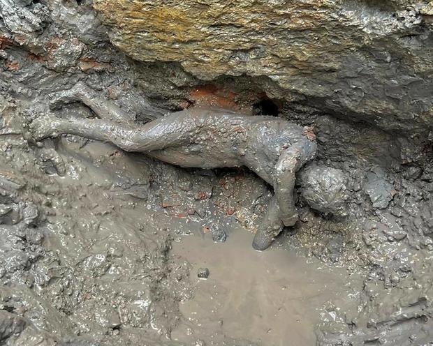 A full body bronze statue covered in mud 