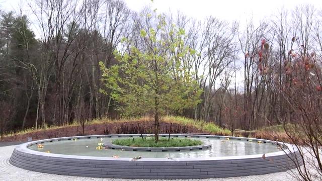 A stone path leads to a sycamore tree in the middle of a reflection pool, and 26 wreaths float in the water, representing the 20 first graders and six educators who were killed. Their names are engraved on the surrounding wall. 