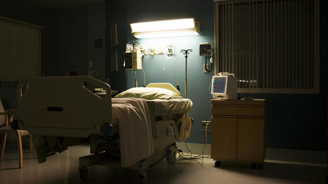 Bed in darkened empty hospital room 