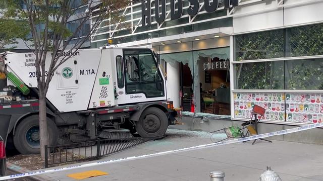 A street sweeper sits in front of a broken window at the Hudson Market eatery. 