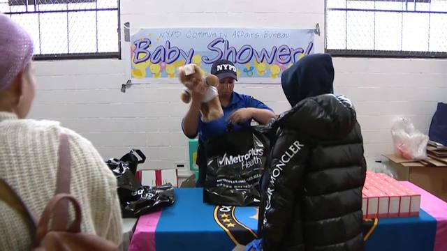 An NYPD official puts a stuffed animal in a bag for a mom-to-be. 
