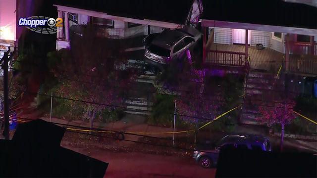 An aerial shot of a vehicle smashed into the front porch of a home. 