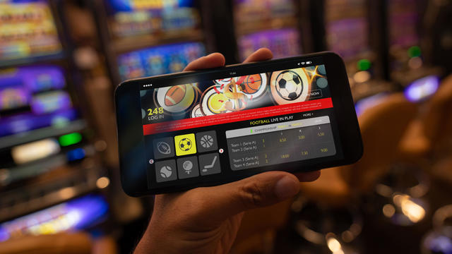 Unrecognizable person holding a smartphone with a sports betting application on screen 